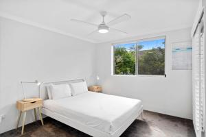 a white bedroom with a bed and a window at Salty Sea Breeze Apartment 500m to waters edge in Gold Coast