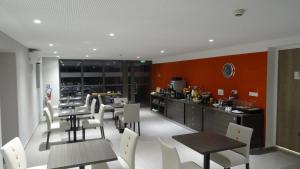 a dining room with tables and chairs and a kitchen at Parc Hôtel Pompadour in Arnac-Pompadour