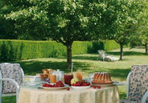 een tafel met eten en fruit erop met twee stoelen bij La Fischhutte, The Originals Relais (Relais du Silence) in Mollkirch