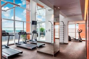 un gimnasio con cintas de correr y elípticas en una habitación con ventanas en Go Inn Hotel Curitiba, en Curitiba
