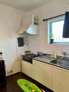 a kitchen with a stove and a sink and a window at P-house Yumearu in Sobe