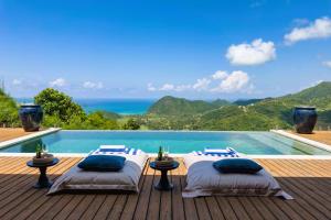 two beds on a deck next to a swimming pool at Selong Selo Resort and Residences in Selong Belanak