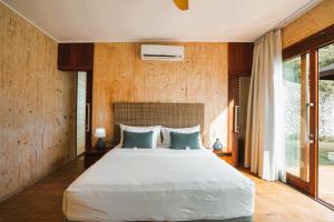 a bedroom with a large white bed and wooden walls at Selong Selo Resort and Residences in Selong Belanak