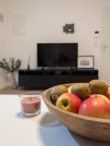 a wooden bowl of apples and a glass of liquid at 2 Zimmer Apartment mit Balkon in Eislingen