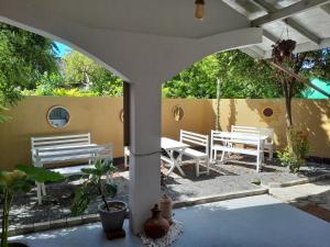 an outdoor patio with white benches and a table at Alkimia in Weligama
