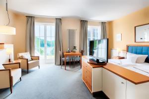 ein Hotelzimmer mit einem Bett und einem Schreibtisch mit Fernseher in der Unterkunft Welcome Hotel Meschede Hennesee in Meschede + 37 Fotos