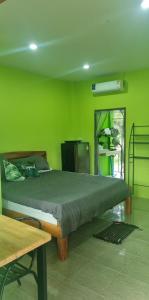 Dormitorio verde con cama y mesa en Lanta Ahad Apartments, en Ko Lanta