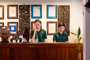 zwei Frauen stehen hinter einem Rezeptionstresen in der Unterkunft La Niche D'angkor Boutique Hotel in Siem Reap + 141 Fotos