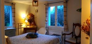 a bedroom with a bed and two chairs and windows at Les Ondines in Estréelles