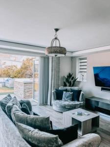 een woonkamer met een bank, twee stoelen en een tv bij Luxury home with Harbour Views in Poole in Poole