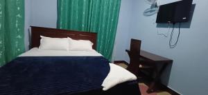 a bedroom with a bed with a television and green curtains at Lasts minute lodge in Boma la Ngombe