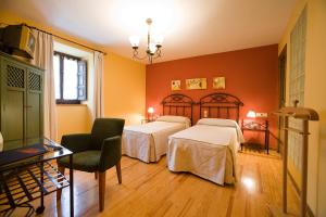 a hotel room with two beds and a chair at Hostal Almadiero in Burgui