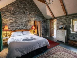 a bedroom with a bed and a stone wall at Traditional style thatched cottage in Kenmare in Kenmare