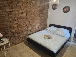a bed in a room with a brick wall at L'Aristide proche gare parking facile in Montauban