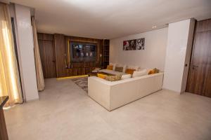 a living room with a white couch and a tv at Élégance et Prestige à Gueliz Appartement 3 chambres in Marrakech