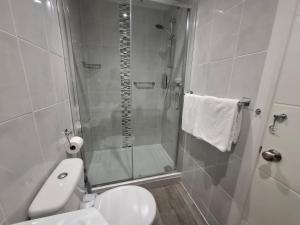a bathroom with a shower and a white toilet at Westbrook Lodge Guest House in Margate