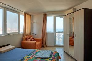 a bedroom with a bed and a chair and windows at Guest House Dima in Sozopol