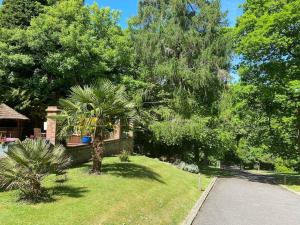 una casa con una palmera en un patio en 4 bedroom Lodge Hotub-Pool in Surrey UK, en East Horsley