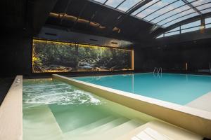 a large swimming pool in a building with a large window at HF Ipanema Park in Porto