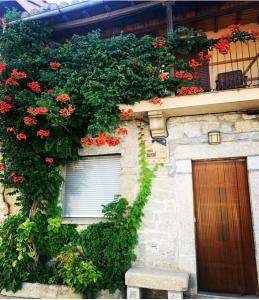 a building with flowers on the side of it at Casa Rural el Comercio Sierra de Francia in San Miguel de Valero