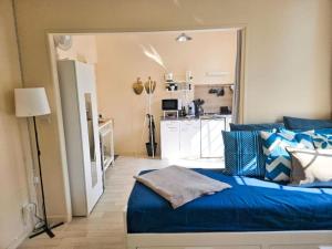 une chambre avec un lit bleu et une cuisine dans l'établissement Appartement lumineux proche Abbaye & Centre de Caen, à Caen