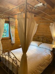 ein Schlafzimmer mit Himmelbett in einer Blockhütte in der Unterkunft 3 Bedroom Lodge Hotub pool in Horsley Surrey UK in East Horsley