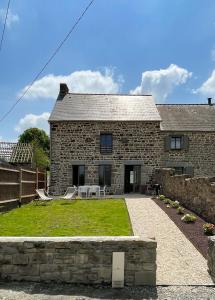 a stone house with a table and chairs in the yard at La Maison de Léon in Saint-Georges-de-Gréhaigne