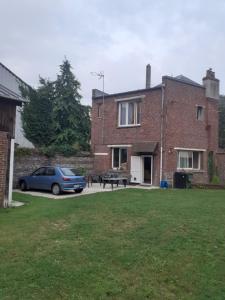 a car parked in front of a brick house at Chez Vincent, Chambre double avec salle de bain, wc et accès privés, très bon emplacement dans Dieppe, au calme, avec Parking Gratuit et Clôturé, terrasse et grand jardin, Animaux admis, pas de cuisine mais micro ondes et bouilloire fournis in Dieppe