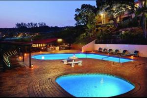 a large swimming pool with a table and chairs next to a building at Shakas rock chalet 20 in Ballito