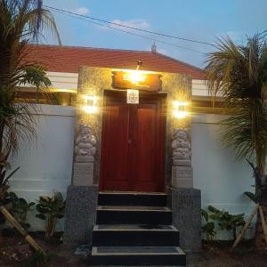 a red door of a house with stairs in front at Prayoga homestay in Nusa Dua