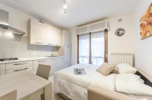 a white bedroom with a bed and a kitchen at Residence Daytona Appartamento due camere in Caorle