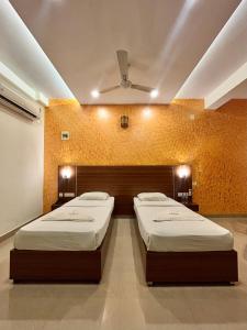 two twin beds in a room with a ceiling at Hotel Citywalk Residency in Mangalore