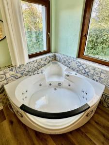 a large bath tub in a bathroom with two windows at private spa in historic villa with pool in Senigallia in Senigallia