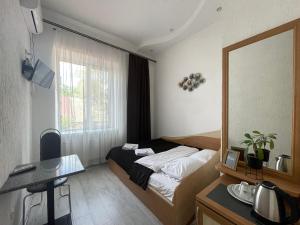 a small bedroom with a bed and a mirror at Hotel Femina in Zhytomyr