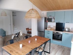 a kitchen and dining room with a wooden table and chairs at maison 6-8 personnes, 300m de la plage in La Guérinière +12 photos