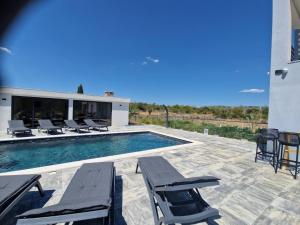 a swimming pool with chairs and a building at Villa JaNi in Donja Jagodnja
