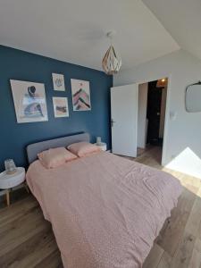 a bedroom with a large bed with a blue wall at Le flamantNoir in Créances