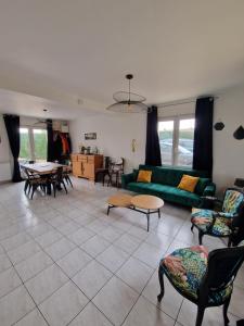 a living room with a green couch and chairs at Le flamantNoir in Créances