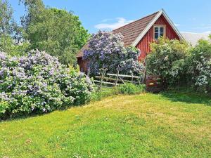 a red barn with purple flowers in front of a yard at 8 person holiday home in GOTLANDS TOFTA in Västergarn