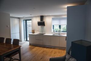 a kitchen with white cabinets and a table and a window at Linhay Cottages 2 in Bathford