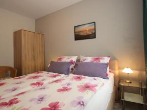 a bedroom with a bed with pink flowers on it at Reihenhaus in Strackholt mit beheiztem Pool in Strackholt +19 photos