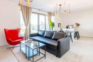 a living room with a couch and a red chair at Bright Flat with Balcony & Comfort in Sanem