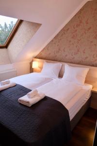 two beds in a attic room with towels on them at Trón Apartman 2 in Siklós
