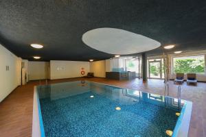 a swimming pool in a house with a large ceiling at Hotel Regina del Bosco in Ronzone