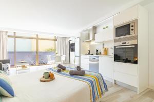 a white room with a bed and a kitchen at HORIZON VACATION HOME - Guest House Gran Canaria in San Bartolomé de Tirajana