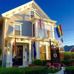 a white house with flags in front of it at Queen Vic Guest House in Provincetown