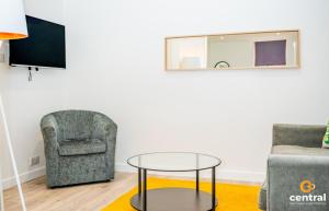 a living room with a chair and a glass table at CENTRAL SERVICED APARTMENTS - 2 Bedroom - Walk Away from City Centre & Universities - Sleeps 4 - 3 x Double Beds - Smart TVs in All Rooms - Short Term Stays Welcome - Walk away from Train & Bus Station - Preferred Location for Short Stay in Dundee in Dundee