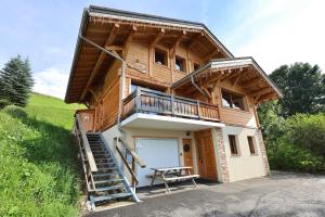 a log house with a porch and a picnic table at Les flocons in Crest-Voland