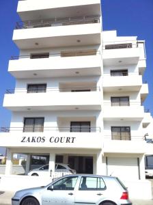 un coche blanco estacionado frente a un edificio en Zakos Court Apartments, en Lárnaca