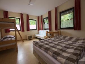 a bedroom with a bed and a chair and windows at Ferienwohnung im Haus Schiefertal, Wieda in Wieda